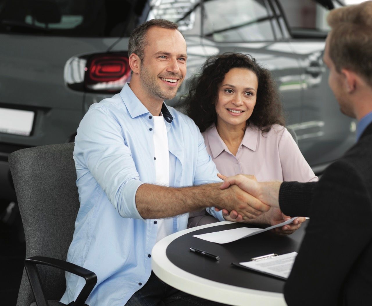 Couple qui serre la main d'un conseiller auto