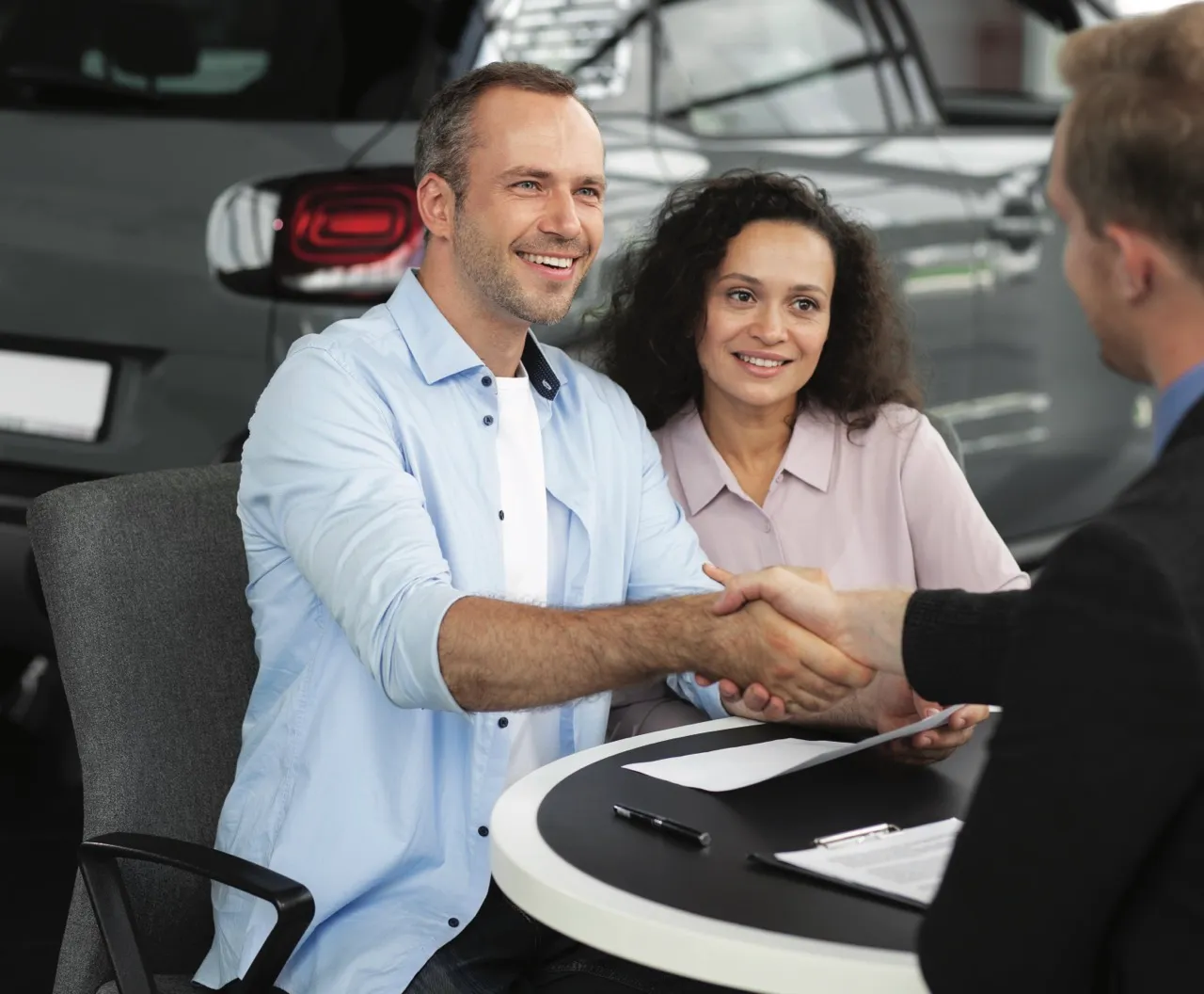 Couple qui serre la main d'un conseiller auto